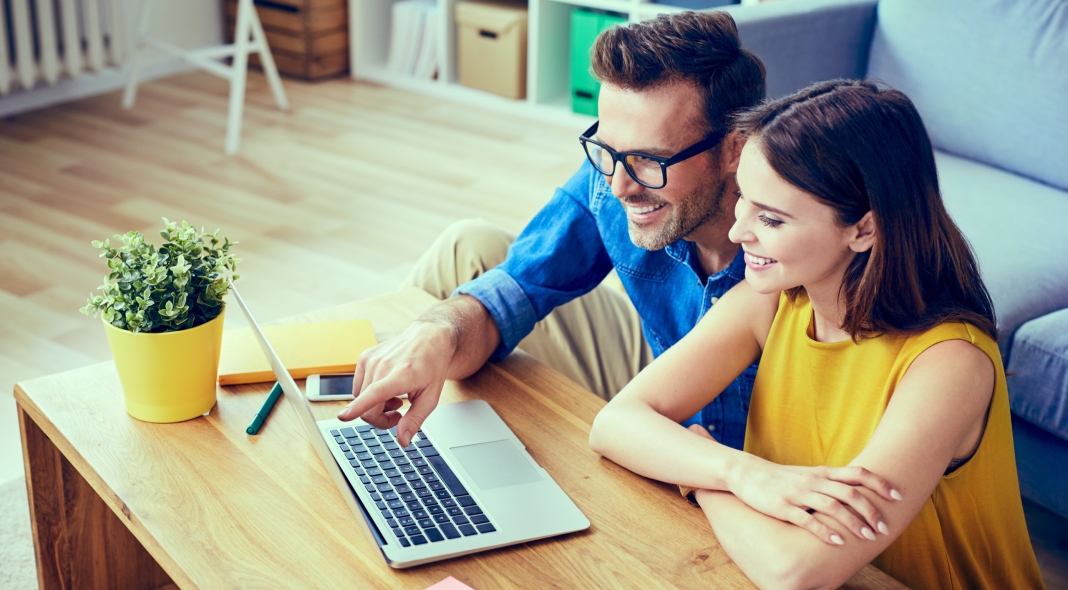 Happy couple with laptop spending time together at home